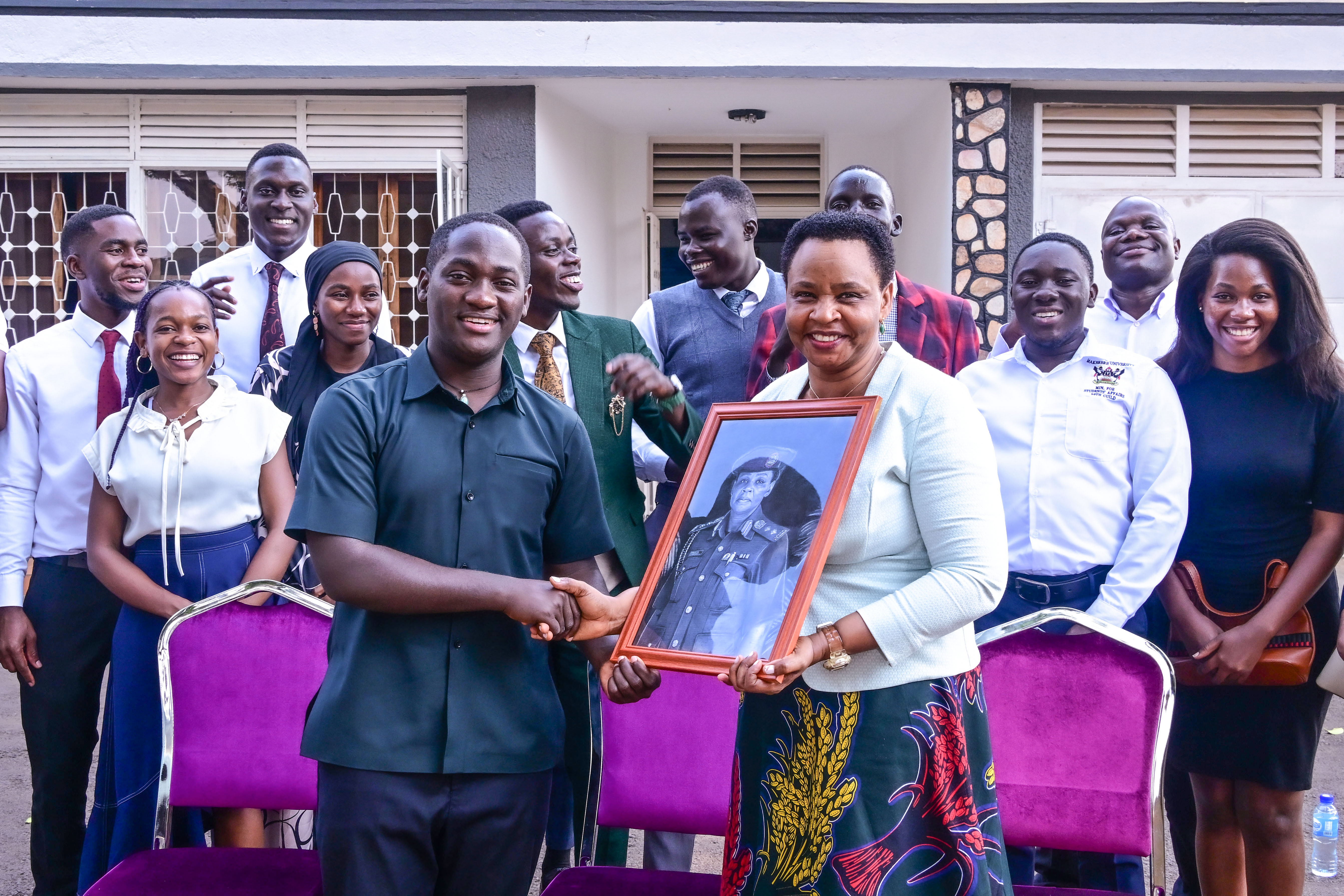 Makerere University Guild President Vincent Lubega Nsamba hands over an artistic portrait to Col. Edith Nakalema head of State House investors protection Unit as his cabinet members look on after a meet 